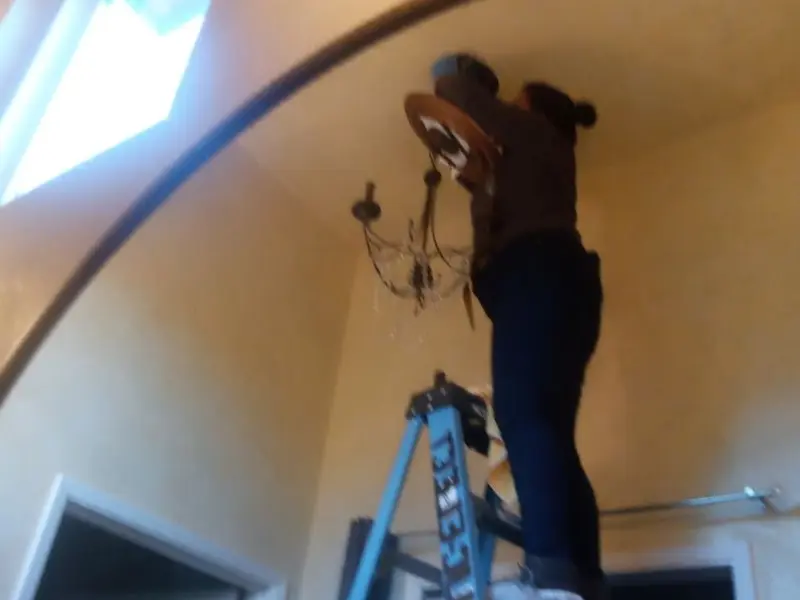 Electrician installing a chandelier in a LaFayette residence